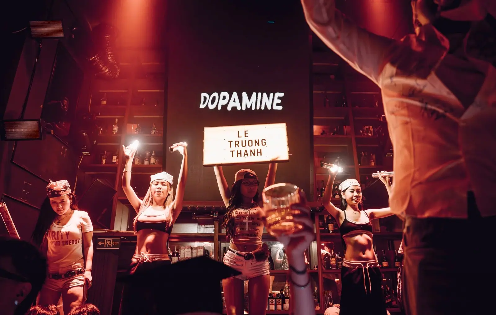 Vũ đoàn cầm đèn giơ cao chào bàn khách dưới chữ Dopamine chiếu trên tường